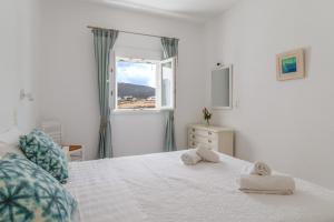 a white bedroom with a bed with towels on it at Afroditi Ftelia Anemone in Mykonos