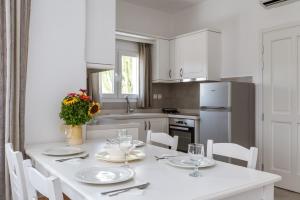 a kitchen with a white table and chairs and a kitchen with at Afroditi Ftelia Anemone in Mykonos