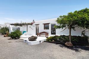 a white house with a bench and a tree at Apartamento Romero in Arrecife