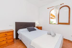 a bedroom with two beds and a dresser and a mirror at Chalet Es Llossar in Cala en Blanes