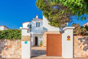 a white house with a wooden garage door at Chalet Es Llossar in Cala en Blanes