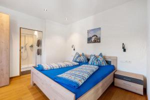 a bed with blue sheets in a white bedroom at Ferienwohnung 3 Weger in Andrian