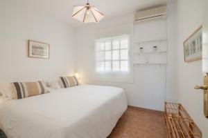 a white bedroom with a white bed and a window at Atico En Islantilla in Huelva +19 photos