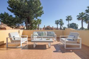 a patio with white furniture and a table and chairs at Atico En Islantilla in Huelva