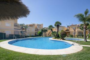 a large swimming pool with palm trees and houses at Atico En Islantilla in Huelva