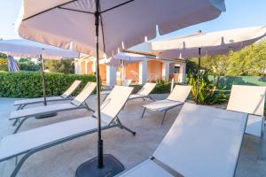 a row of white chairs and umbrellas on a patio at Villa Leale Plemmirio con piscina in Syracuse