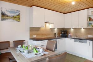 a kitchen with white cabinets and a wooden table at Haus Bergfrieden in Au im Bregenzerwald +14 photos