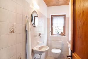 a white bathroom with a toilet and a sink at Haus Bergfrieden in Au im Bregenzerwald