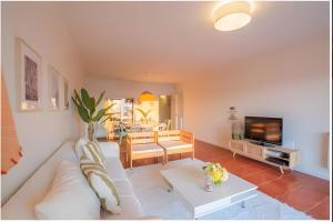 a living room with a white couch and a tv at T3 Moledo Com Piscina e Vista Mar in Moledo