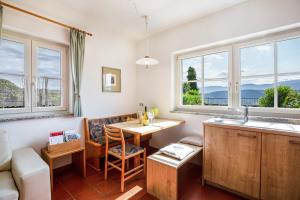 a kitchen with a table and a couch and windows at Weingut Lieselehof Apt Aurora in Caldaro