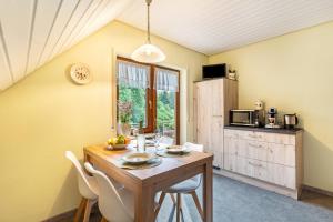 a kitchen with a wooden table and white chairs at Furtwengler in Oberharmersbach