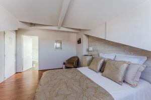 a bedroom with a large bed with white sheets and pillows at La Chambre Dorée du Bassin in La Teste-de-Buch