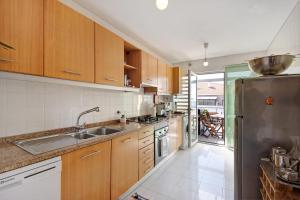 a kitchen with wooden cabinets and a stainless steel refrigerator at Cantinho da Praia da Barra in Gafanha da Nazaré