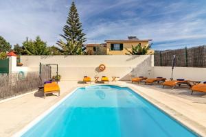 a pool with orange chairs and a house at Villa Retiro in Canhas