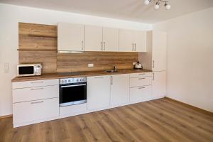 an empty kitchen with white cabinets and a sink at Ferienwohnung Häfele 2 in Bad Wurzach
