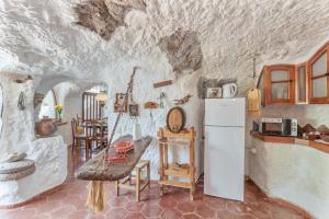 a kitchen with a table and a refrigerator in a cave at Finca Cuevas La Solana in Gáldar