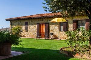 a stone house with an umbrella in the yard at Il Cancellone - Tartaruga in Montiano