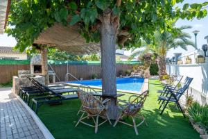 a table and chairs under a tree next to a pool at Traditional Villa in Creixell