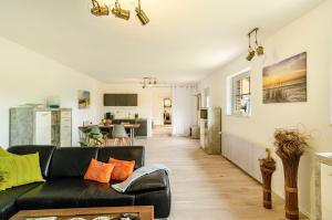 a living room with a black couch and a kitchen at Möwchen in Berumbur
