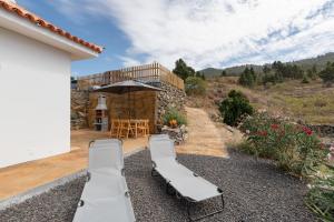 a patio with two lounge chairs and an umbrella at Casa Tajinaste in Tijarafe