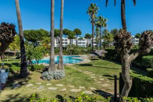 a resort with a swimming pool and palm trees at 2bed apartment in Miraflores in Mijas