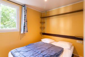 a small bedroom with a bed and a window at Mobilhome Le Chene in Saint-Pompont