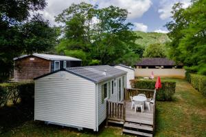 a small white shed with a deck and a table at Mobilhome Le Chene in Saint-Pompont