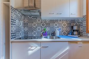 a kitchen with a sink and a tiled wall at La maisonnette en bois in Saumos
