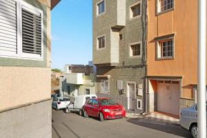 a red car parked on a street next to a building at Little Gem in Cruce de Arinaga