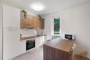 a kitchen with white cabinets and a wooden counter top at Ghome and Home Lake view Apartment in Civenna