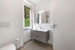 a white bathroom with a sink and a window at Ghome and Home Lake view Apartment in Civenna +18 photos