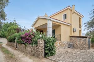 a house with a stone wall and flowers at Casa Miranda in Kefallonia