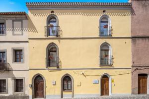 a yellow building with windows and balconies at Affittacamere Le Muse in Scano Montiferro