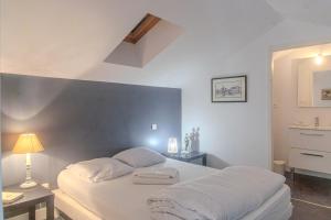 a white bedroom with a bed and a lamp at Villa au bord de la Charente in Jarnac
