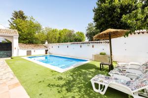 a swimming pool with lawn chairs and an umbrella at Cortijo Caracate in Archidona
