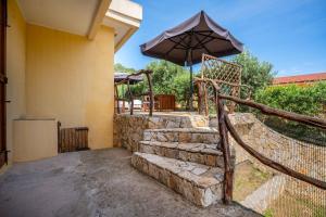 a patio with an umbrella and some stairs at Villa Costa Paradiso del Sud in Costa Rei