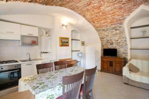 a kitchen and dining room with a table and a brick wall at Le scale, borgo dei pescatori in Cervo +15 photos