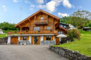 a large wooden house with a balcony on a hill at Chalet La Sportive in Cornimont
