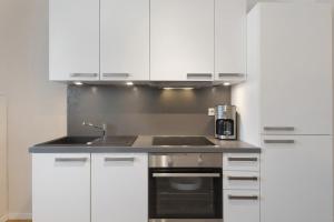 a kitchen with white cabinets and a sink at Torhaus Schloss Wocklum in Balve