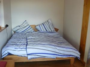 a bed with blue and white sheets and pillows at Ferienwohnung Naturhaus, 50qm in Allensbach