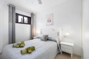 a bedroom with a white bed with two green pillows on it at Sol y mar in Sanlúcar de Barrameda