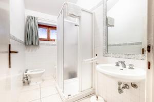 a white bathroom with a shower and a sink at La Capannuccia C in Ansedónia