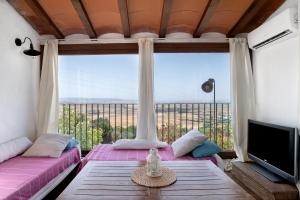 a living room with two beds and a large window at Casa De Los Pintores Facinas in Facinas