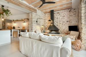 a living room with a white couch and a stone wall at Ca la Pasita 28 in Beniali