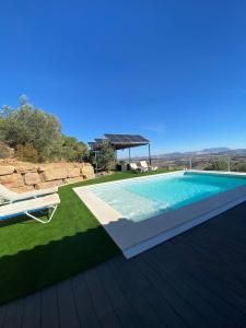 a swimming pool on top of a green lawn at Miralvalle in El Gastor