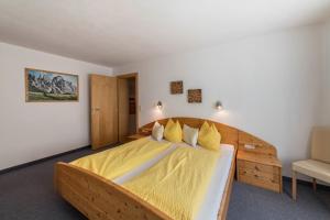 a bedroom with a large wooden bed with yellow sheets at Ferienwohnung Valentina in Schwendau