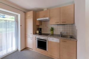 a kitchen with wooden cabinets and a sink and a window at Ferienwohnung Valentina in Schwendau +18 photos