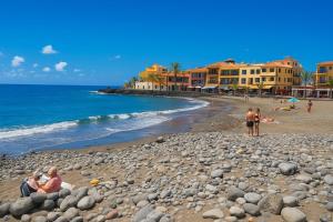 a group of people sitting on a rocky beach at Casa Palmar La Gomera in Valle Gran Rey