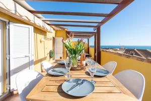 a dining table with white chairs and a view of the ocean at Modern penthouse in Fuengirola