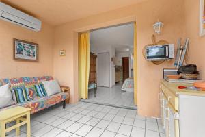 a living room with a couch and a tv at Studio Saint Clair pieds dans l'eau in Le Lavandou